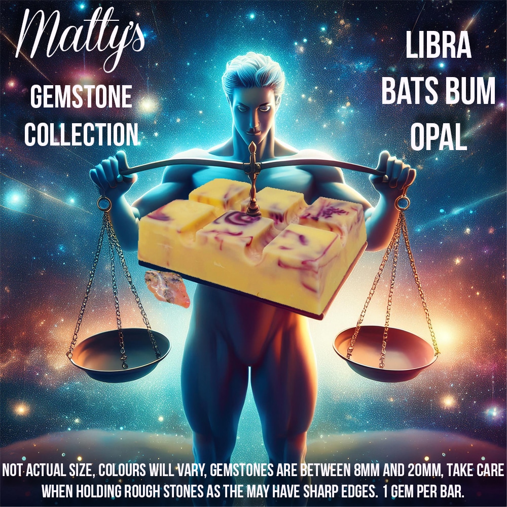 A brightly colored advertisement for "Matty's Gemstone Collection" featuring a muscular figure holding scales with gemstone soap bars. Text reads "Libra Bats Bum Opal," and includes a disclaimer about sizes and the sharp edges of rough stones.