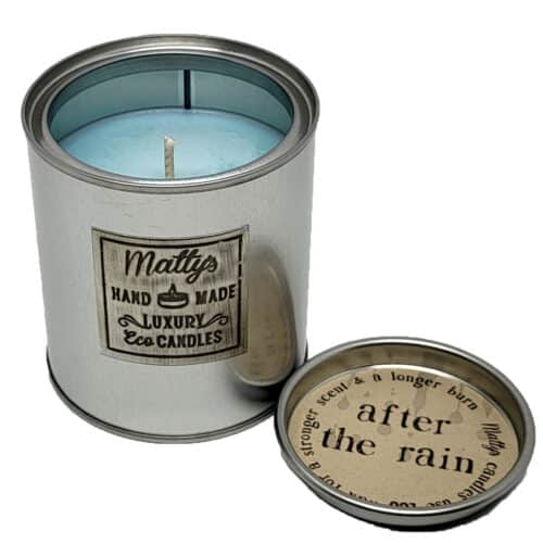 A silver tin holds the "After the Rain Scented Candle," featuring a blue wax and labeled "Matty's Handmade Luxury Eco Candles." With the lid off, it reveals a fresh, rain-inspired scent—ideal for lovers of clean aromas or unique perfume vibes.